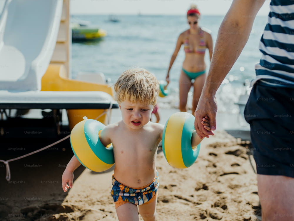 Una familia con dos niños pequeños caminando por la playa en vacaciones de verano.