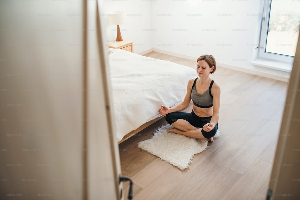 A high-angle view of young woman doing yoga exercise indoors in a bedroom. Copy space.