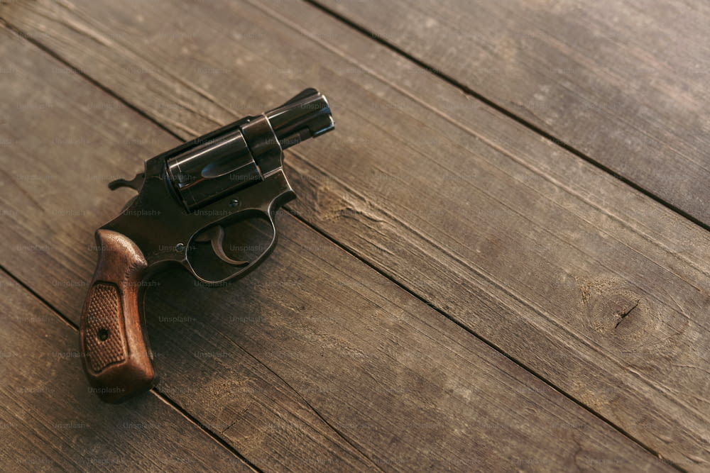 Un revolver sul tavolo di legno, spazio di copia.