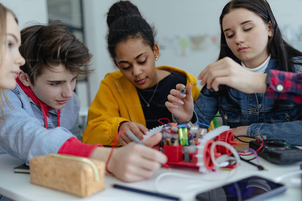 ロボット教室で電動玩具やロボットを組み立ててプログラミングする高校生のグループ