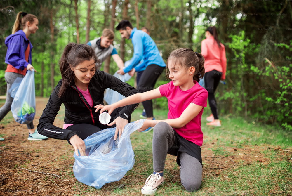 A roup of active young people picking up litter in nature, a plogging concept.