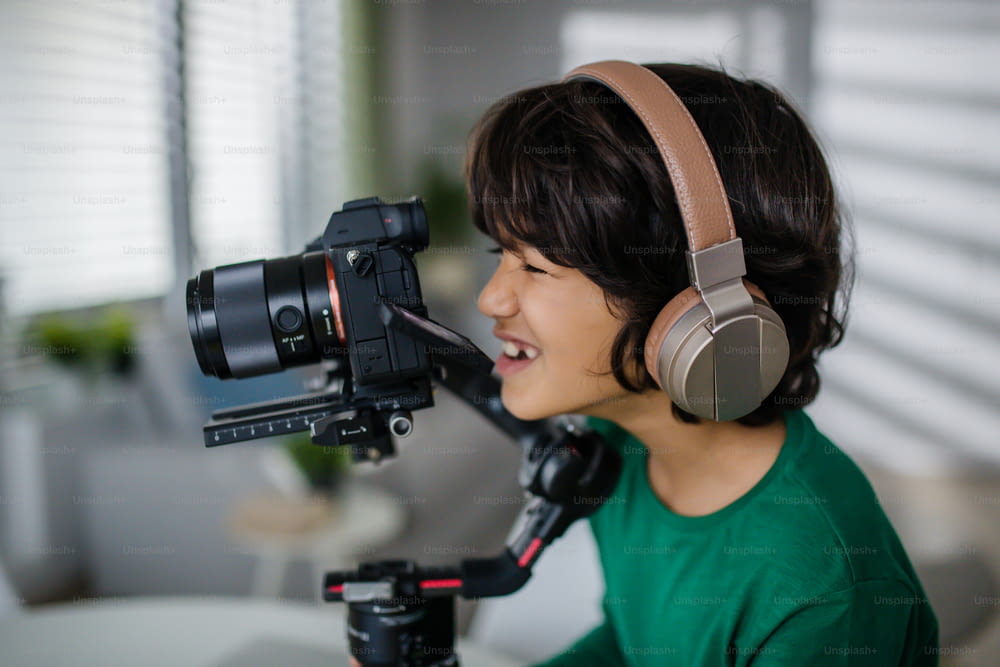 A happy multiracial boy cameraman amateur with headphones at home.