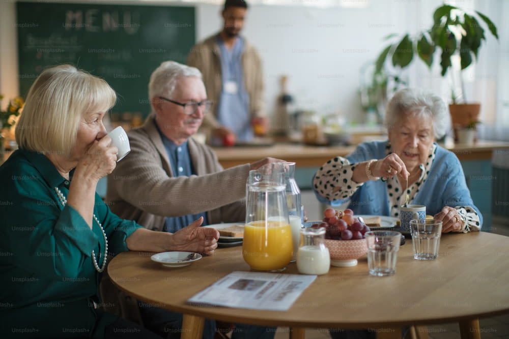 A group of cheerful seniors enjoying breakfast in nursing home care center.