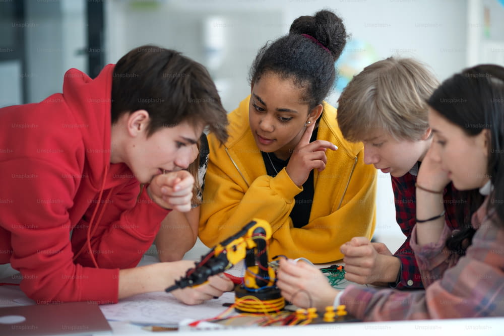 Um grupo de estudantes construindo e programando brinquedos elétricos e robôs na sala de aula de robótica