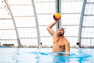 Water polo player in a swimming pool. Man doing sport.