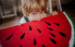 幼児の男の子のクローズアップは、果物のコンセプトを食べて、自宅で屋内で大きなおもちゃの果物で遊んでいます。
