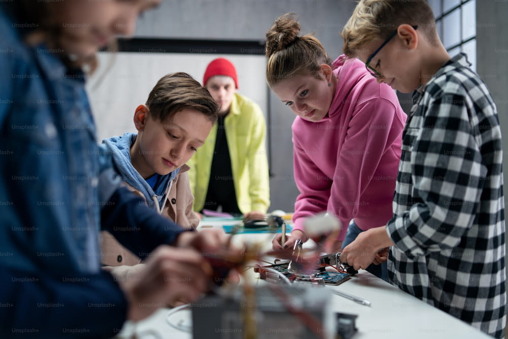 로봇 교실에서 전기 장난감과 로봇을 가진 과학 교사와 함께 행복한 아이들 그룹