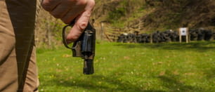 Um homem irreconhecível com revólver se preparando para atirar alvo em campo de tiro ao ar livre.