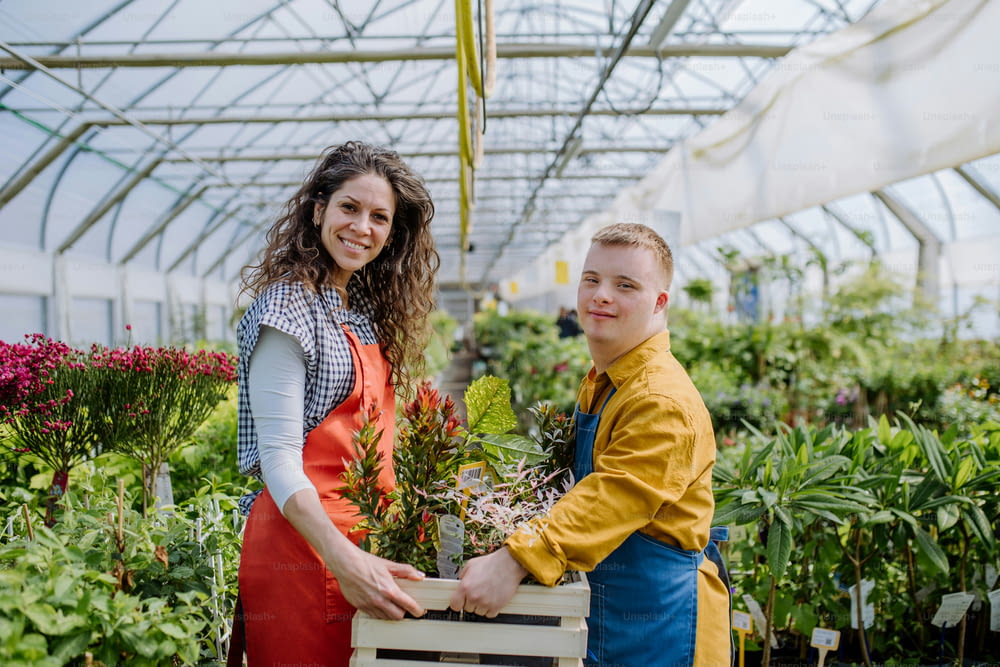 정원 센터에서 다운 증후군을 앓고있는 젊은 직원을 돕는 경험 많은 여성 꽃집.