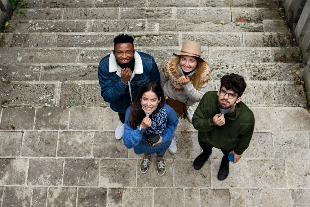 Ritratto vista dall'alto del gruppo di giovani all'aperto in città, guardando la macchina fotografica. Concetto di coronavirus.
