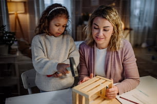 Una bambina felice che ristruttura una cassa di legno insieme a sua madre a casa.