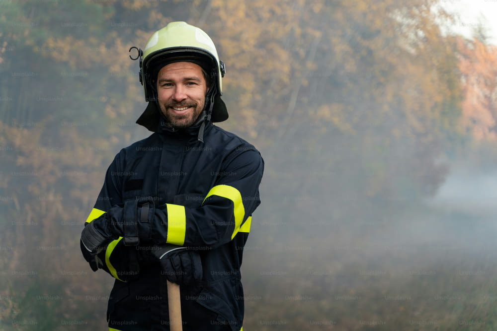 A portrait of happy firefighter man looking at camera after successful action in forest