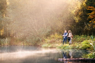 Couple de personnes âgées actif pêchant au lac. Une femme et un homme dans une belle nature d’automne au petit matin.