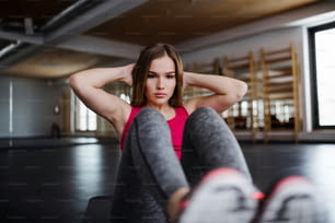 A portrait of a beautiful young girl or woman doing exercise in a gym.