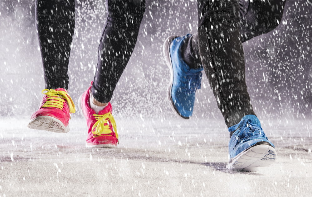 Mulher atleta está correndo durante o treinamento de inverno fora em clima de neve fria.