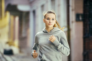 Junge Läuferin joggt auf gefliestem Bürgersteig Altstadt im Zentrum. Gesunder Lebensstil.