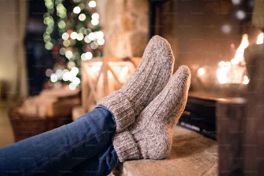 Piedi di donna irriconoscibile in calzini di lana accanto al camino di Natale. Concetto di vacanze invernali e natalizie.