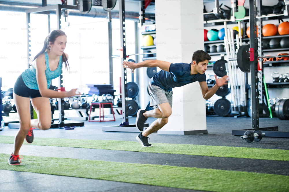 체육관에서 빠르게 달리는 젊은 커플. 강렬한 훈련 세션을 하는 젊은 남녀. 체육관에서 스포츠 훈련.