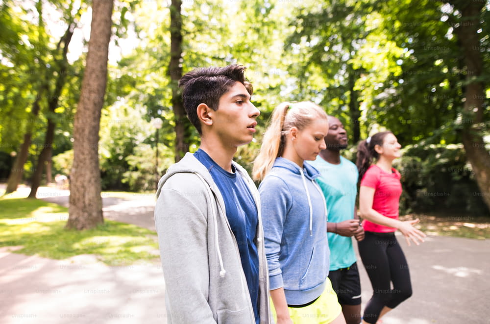 Groupe de jeunes athlètes préparés pour la course dans un parc d’été vert et ensoleillé.