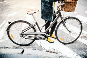 Mujer joven irreconocible con bicicleta en la soleada ciudad de la primavera.