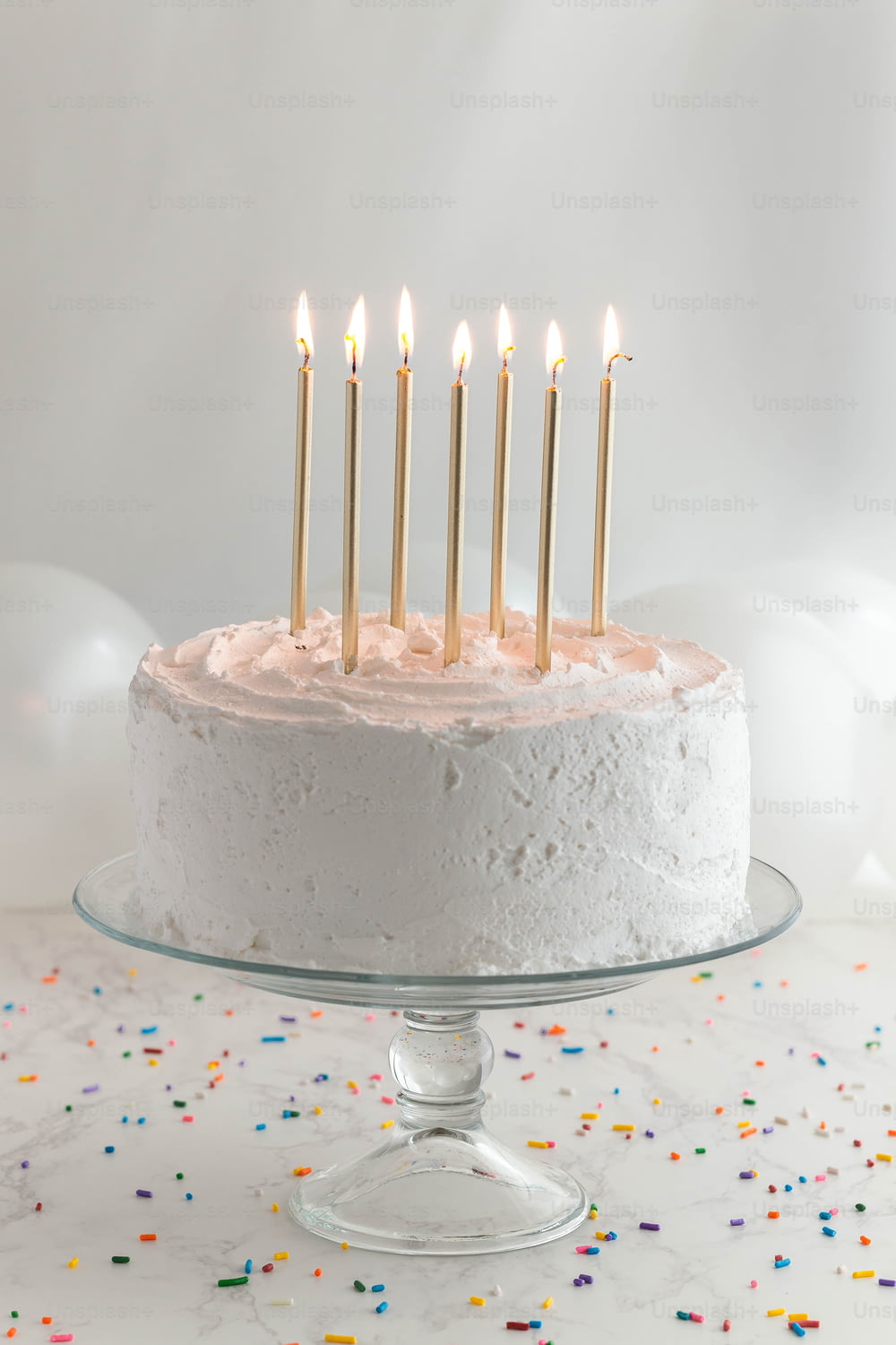 una torta di compleanno con glassa bianca e candele accese