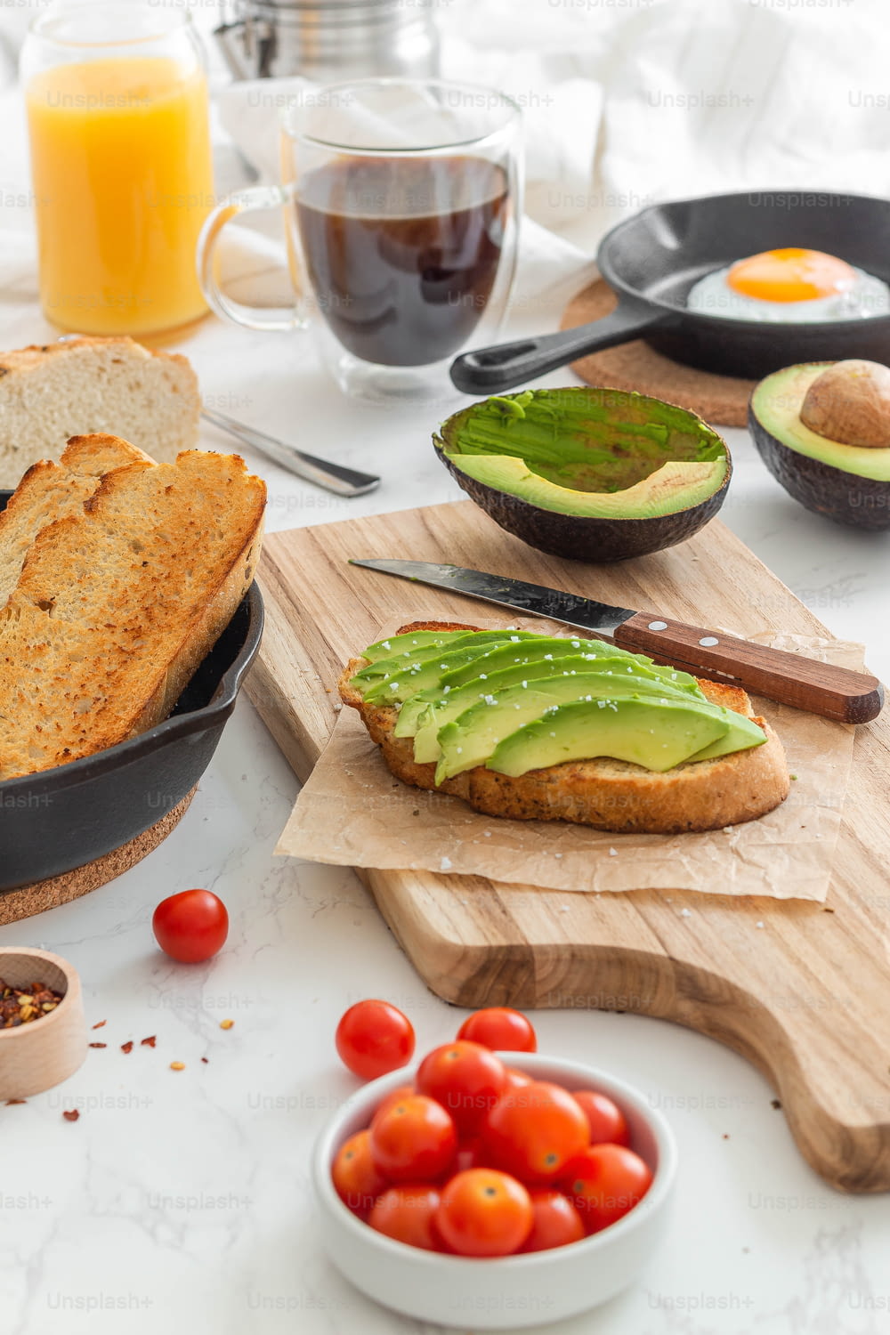 a table topped with bread, avocado and tomatoes
