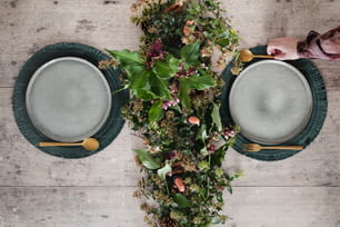 a table topped with plates covered in greenery