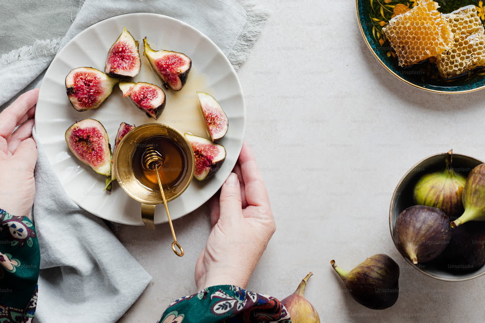 a person holding a plate of figs and honey