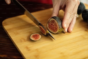 a person cutting up a piece of fruit on a cutting board