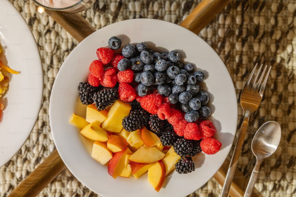 a white plate topped with fruit next to a bowl of fruit