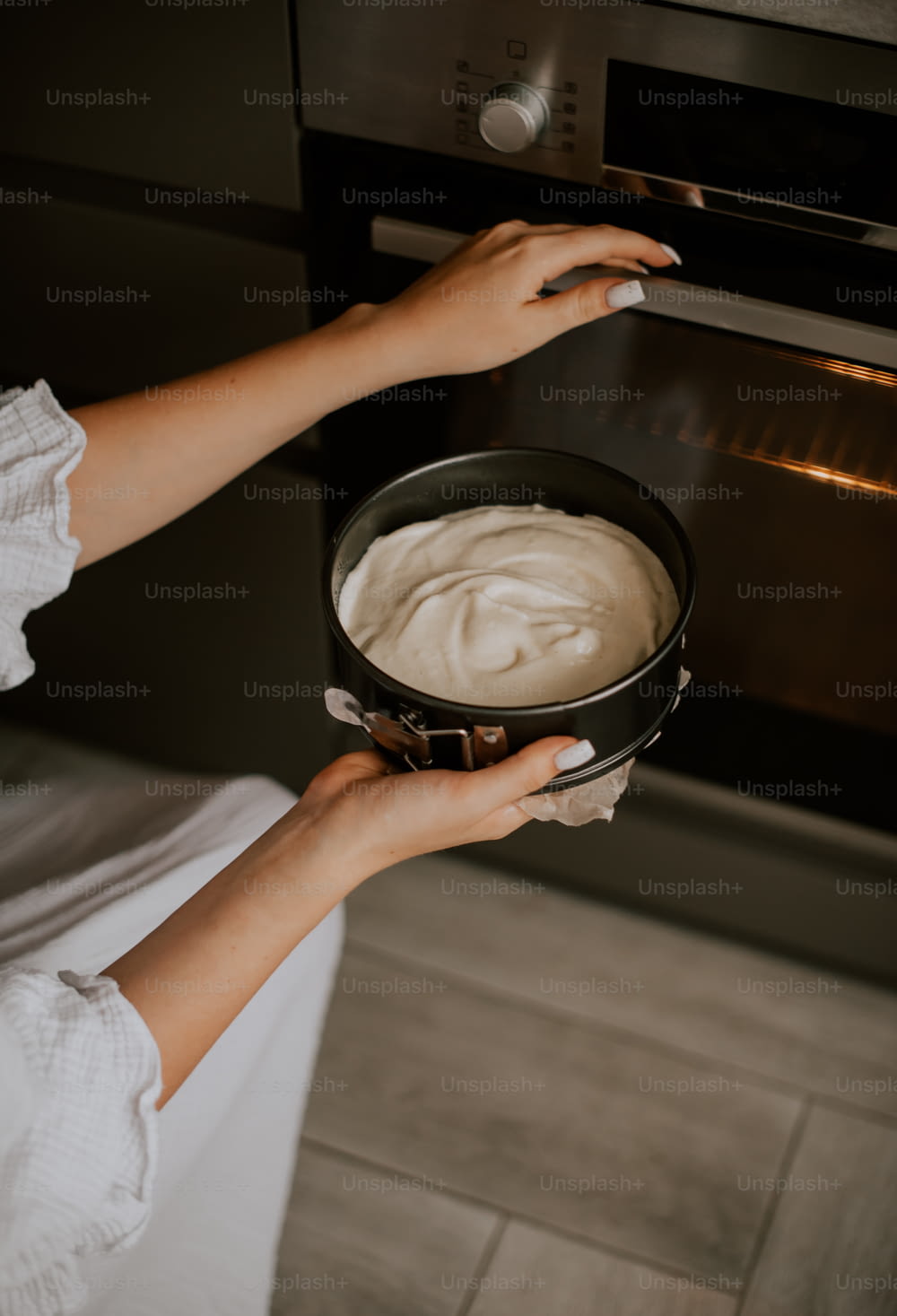 a person holding a pan of food in front of an oven