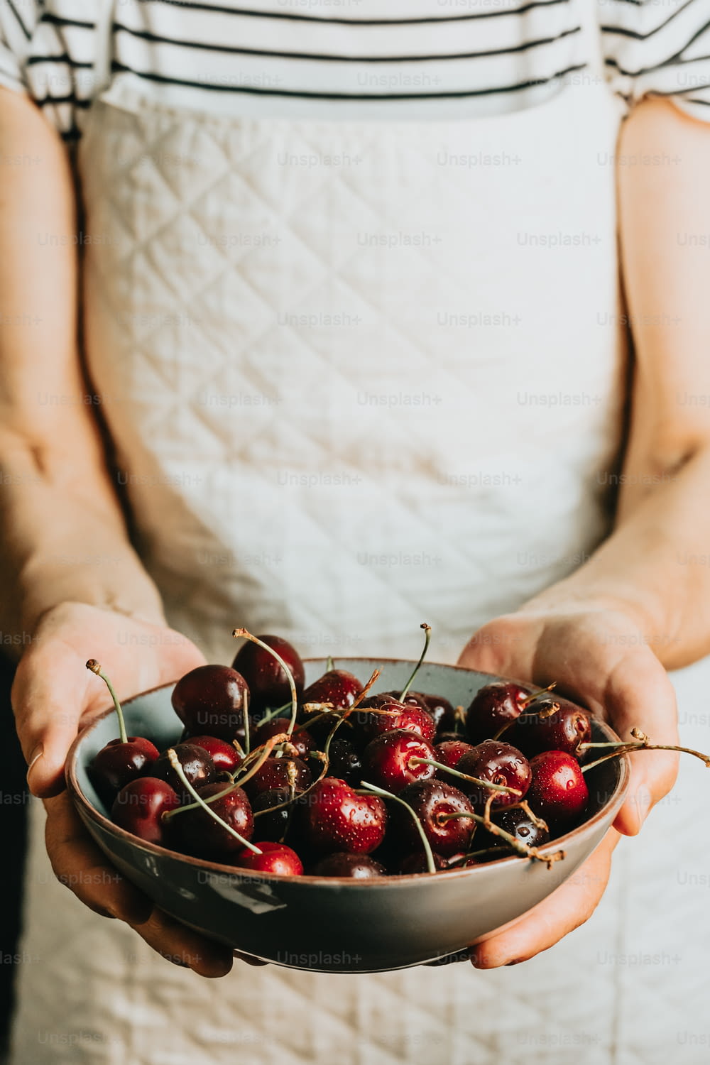 a person holding a bowl of cherries in their hands