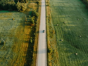 a car driving down a country road in the middle of a field