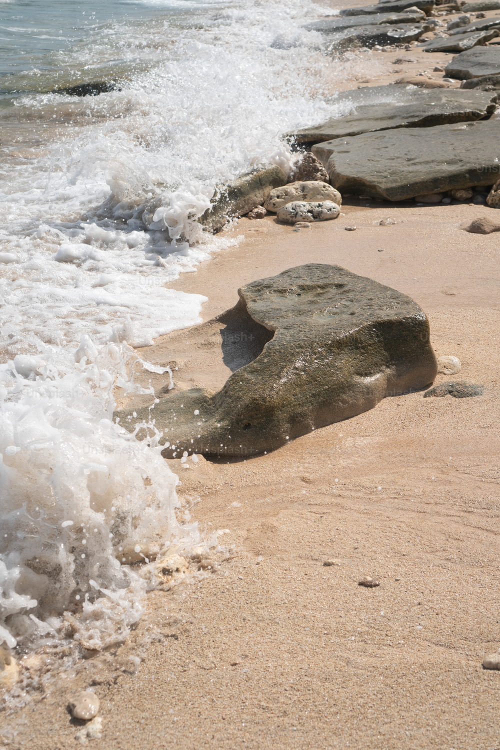 Ein Felsen, der am Strand neben dem Meer liegt