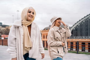 Cheerful young women wearing hijab laughing and walking in the street.