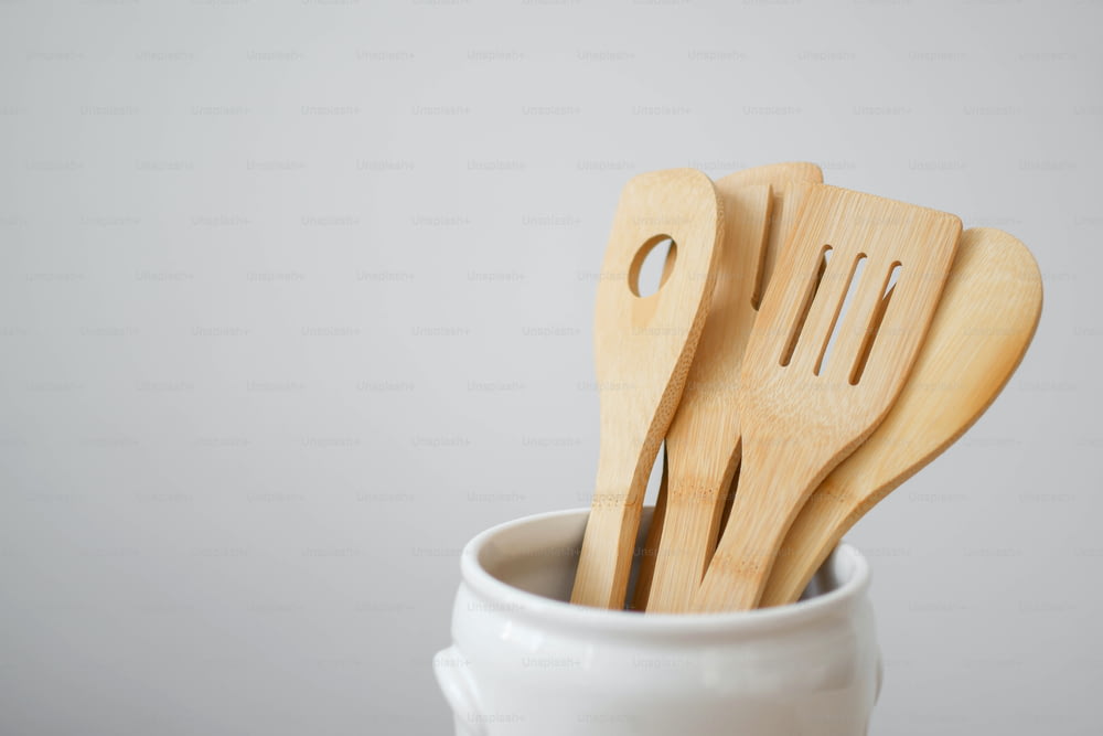 three wooden utensils in a white cup