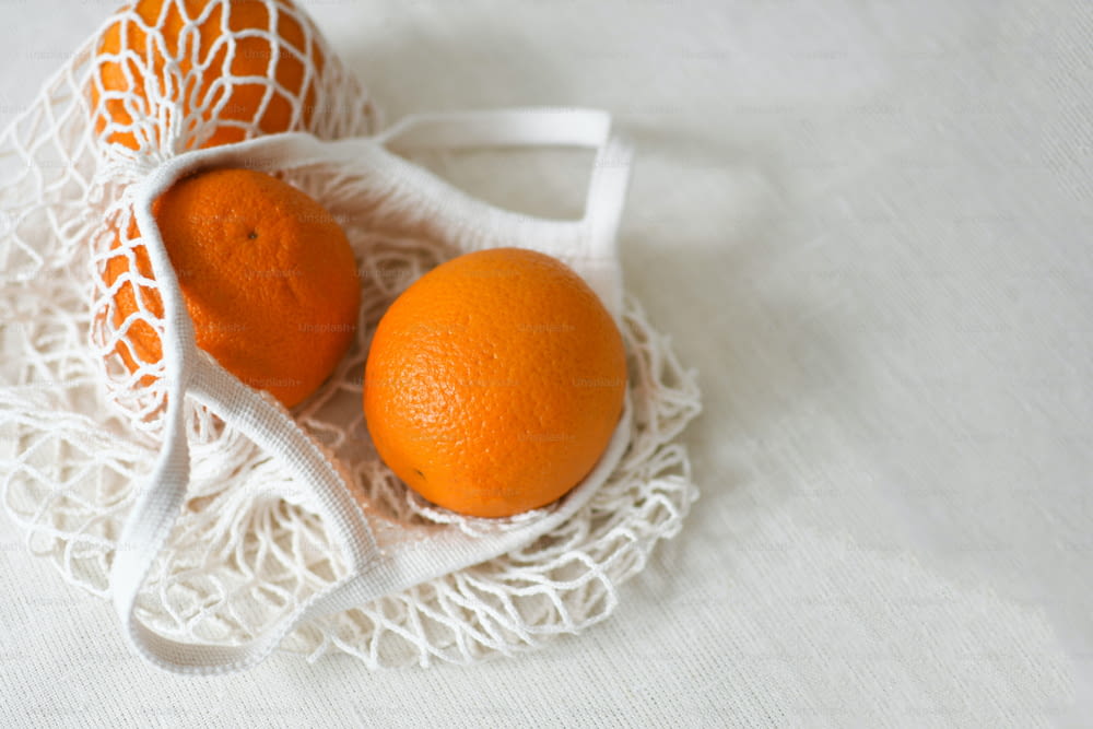 two oranges in a white bag on a white cloth