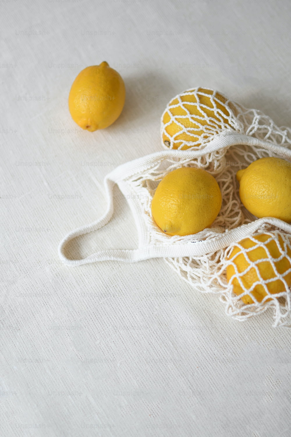 three lemons in a net bag on a table