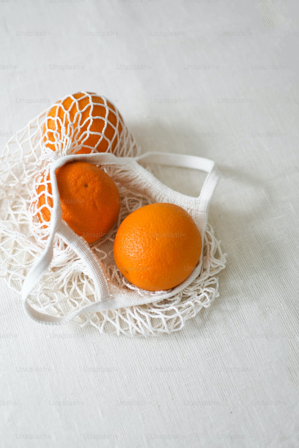 two oranges sitting on a white table cloth