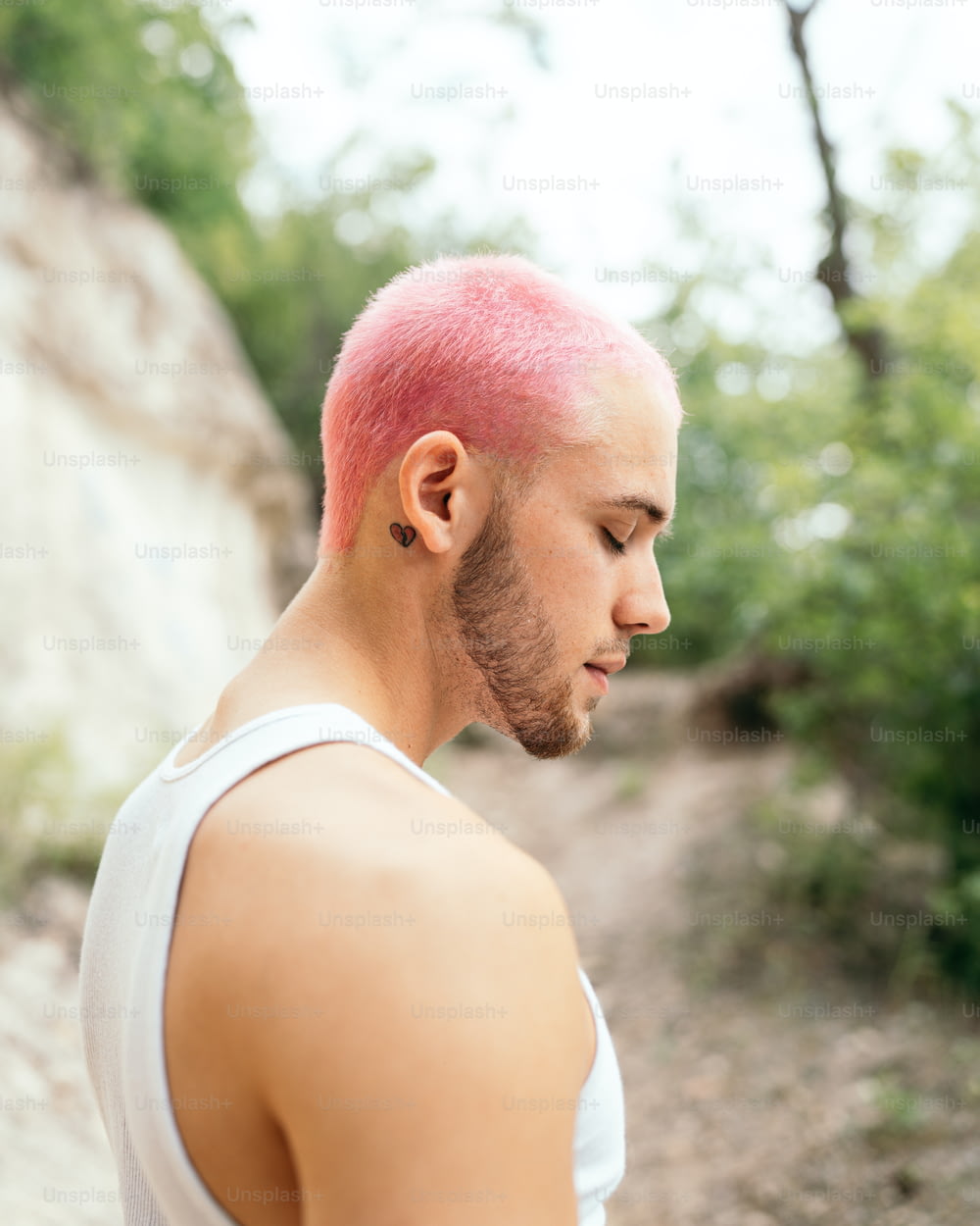 a man with pink hair and a white tank top