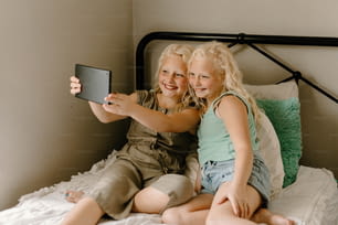 Due bambine che si siedono su un letto che scattano una foto