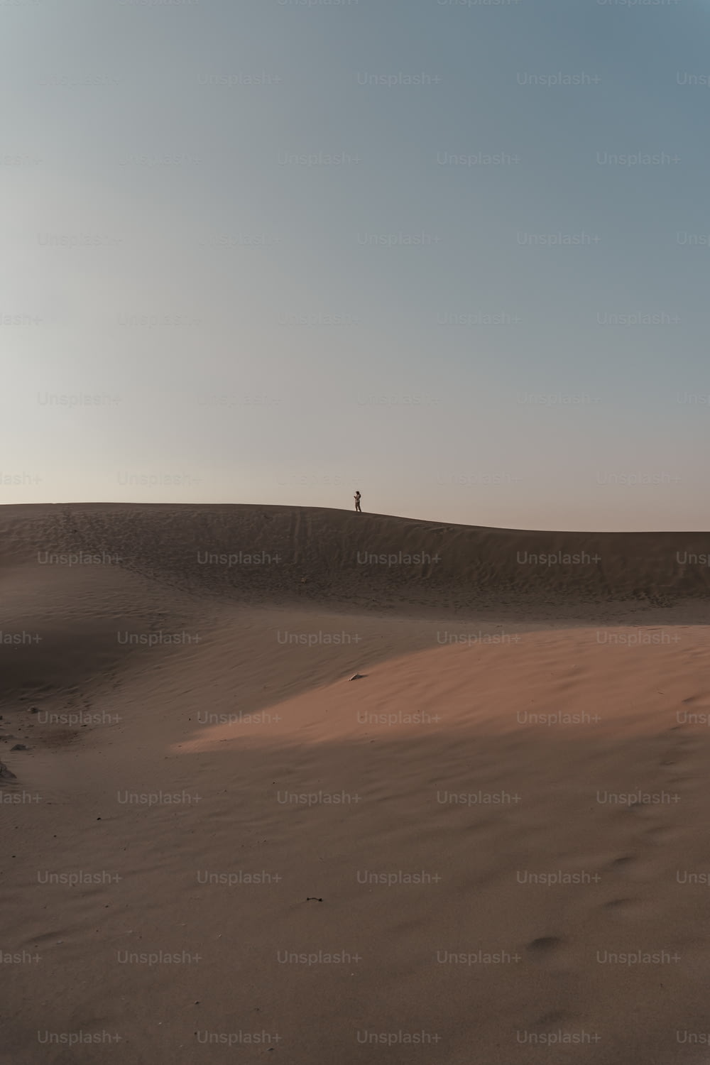Una persona parada en la cima de una duna de arena