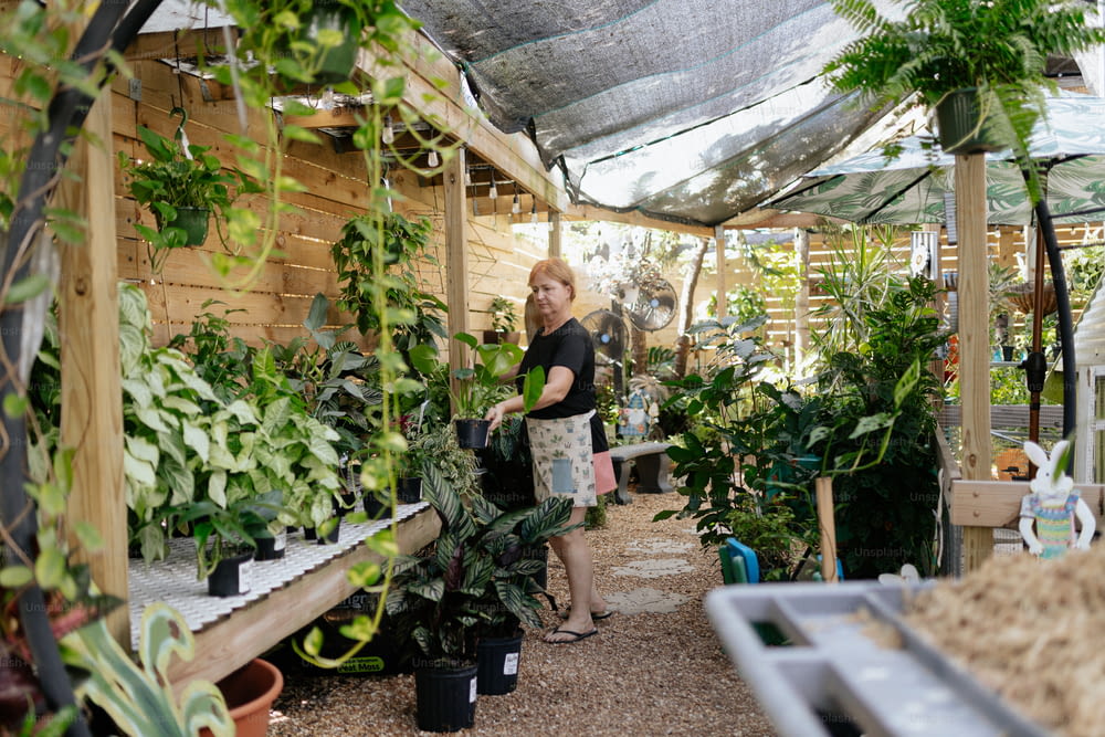 a woman standing in a greenhouse with lots of plants