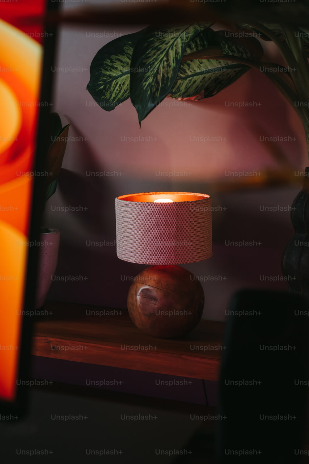 une lampe qui se trouve sur une table à côté d’une plante en pot