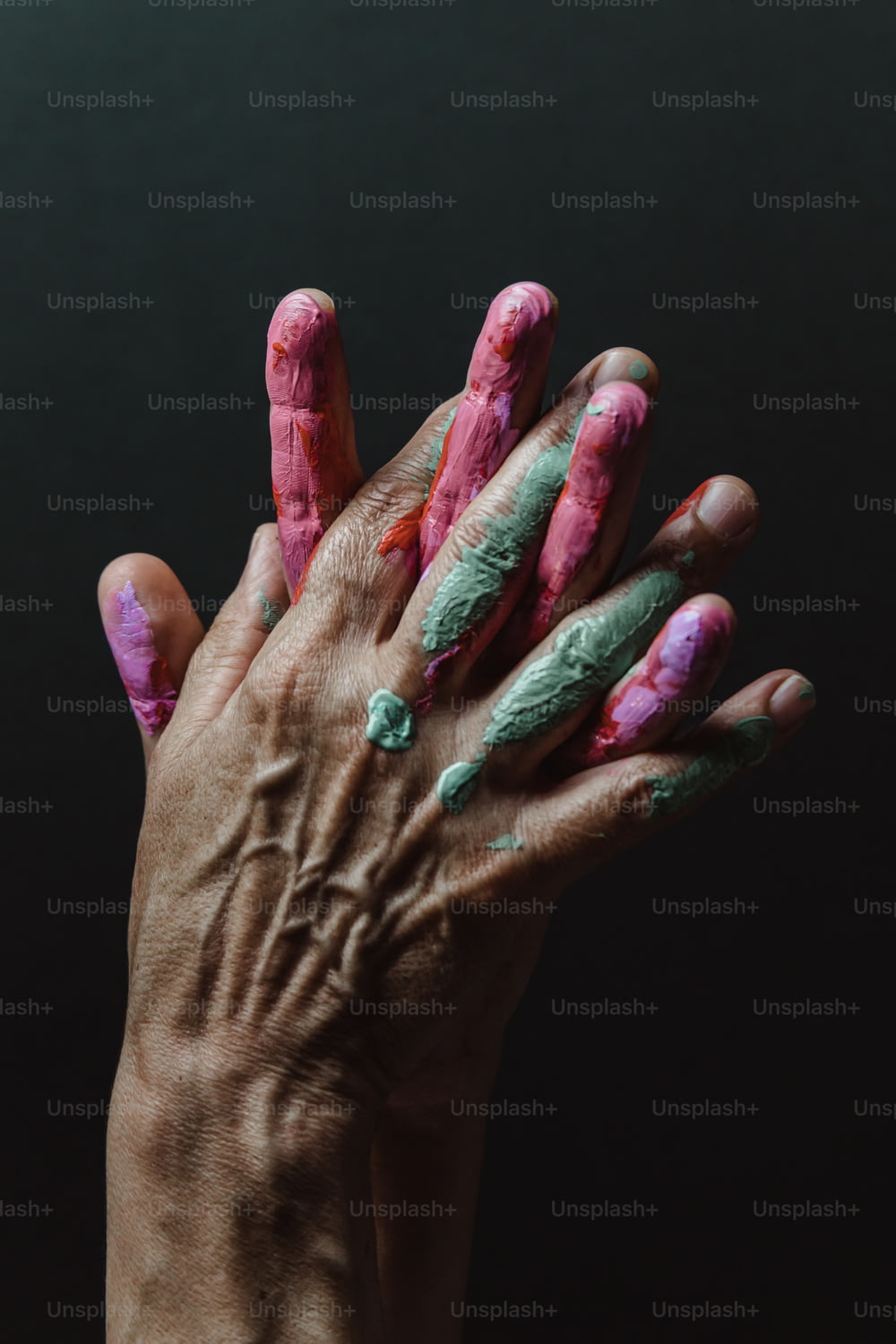 ピンクと緑の絵の具が塗られた人の手