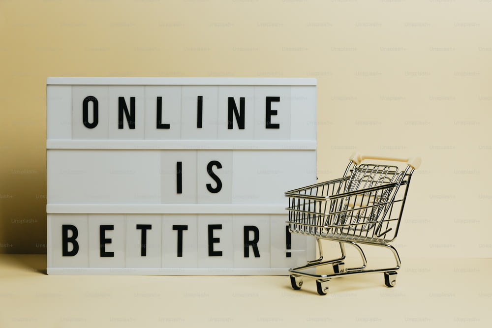 Un carrello della spesa accanto a un cartello che dice online è meglio