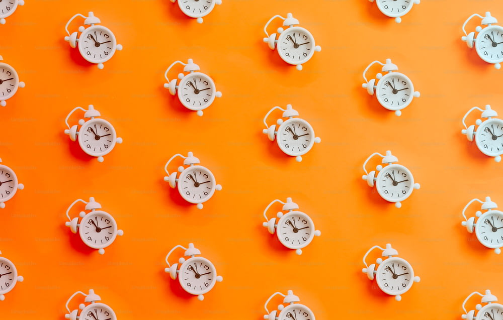 Un gruppo di orologi bianchi su una parete arancione