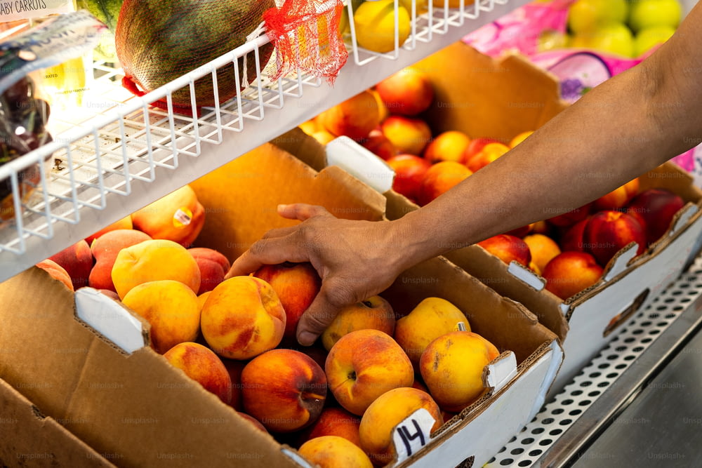 a person reaching for a box of peaches