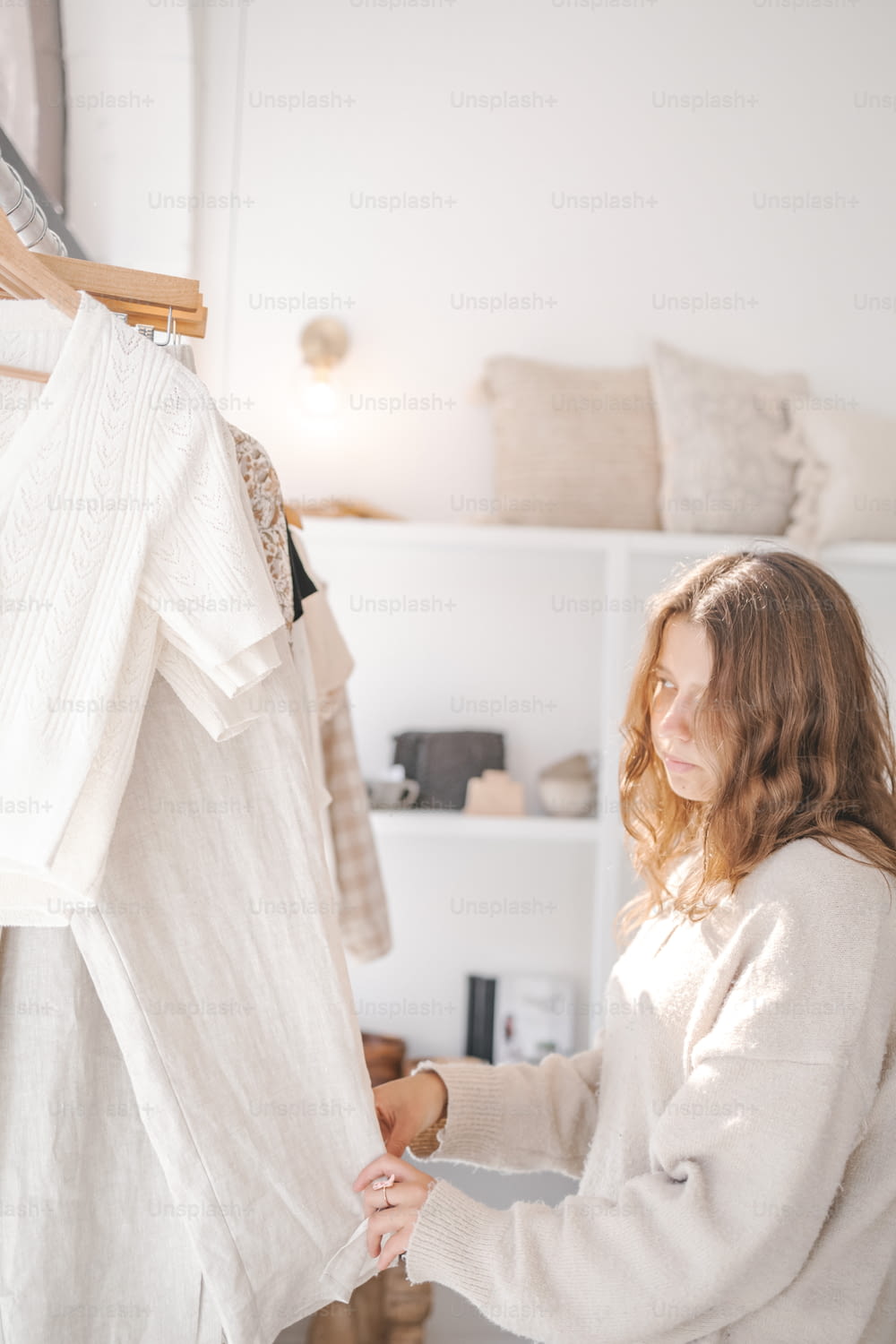 a woman looking at a white shirt hanging on a rack