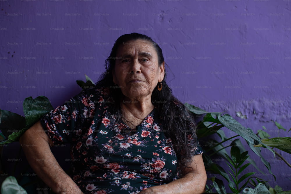 Una donna seduta di fronte a un muro viola